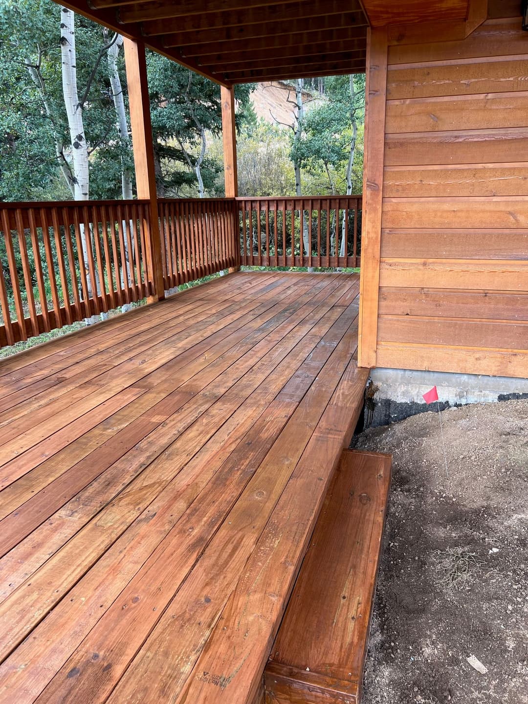Wooden deck with stairs, surrounded by trees and natural scenery, showcasing craftsmanship.