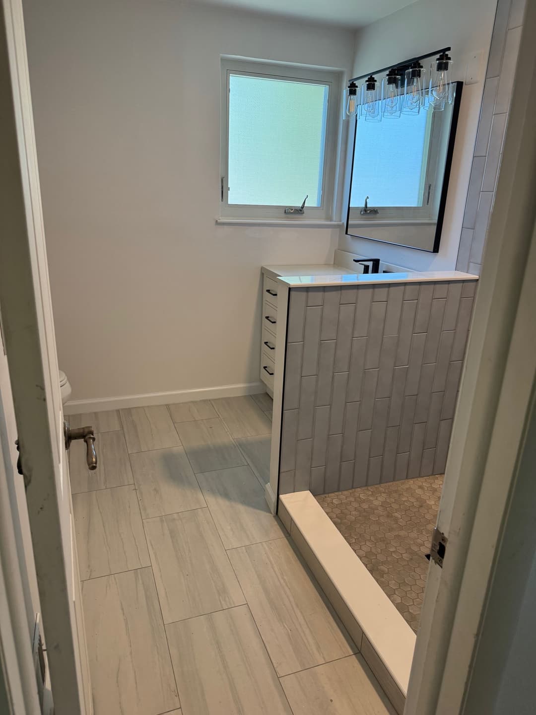 Modern bathroom with a walk-in shower, large window, and stylish tile flooring.