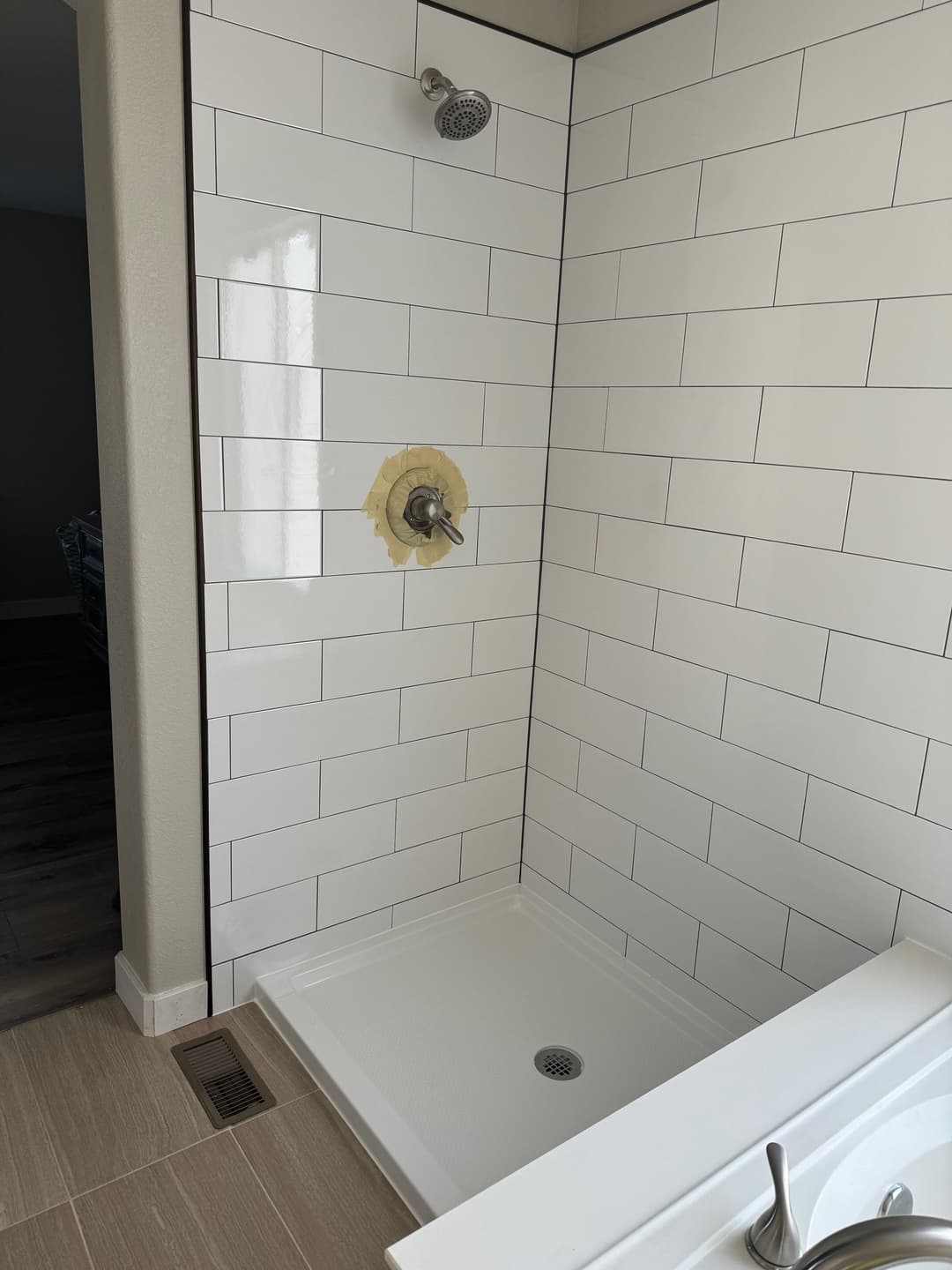 Modern shower with white tiled walls, uninstalled faucet, and minimalistic design elements.