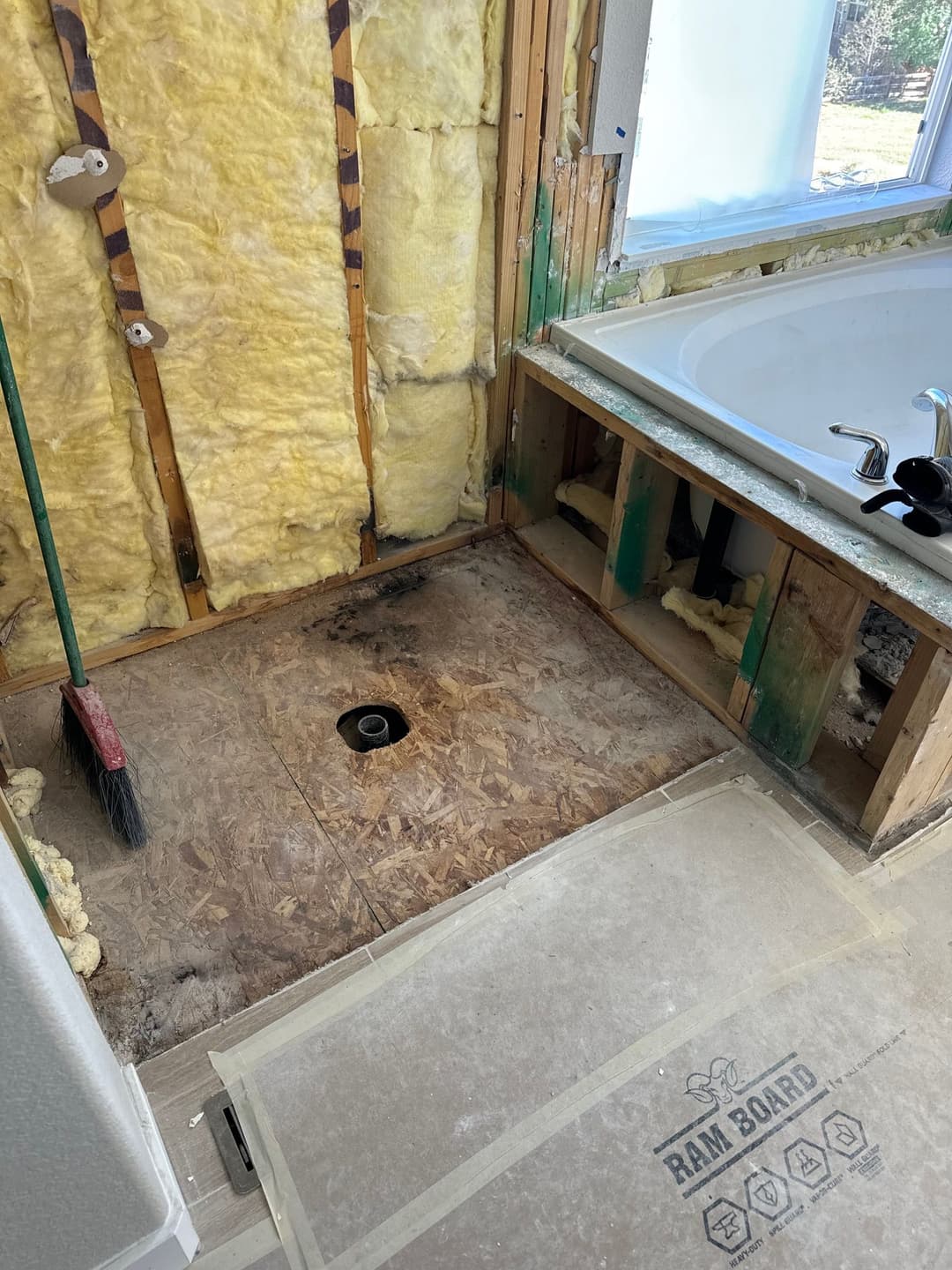 Bathroom renovation in progress with exposed walls, floor, and plumbing preparations.