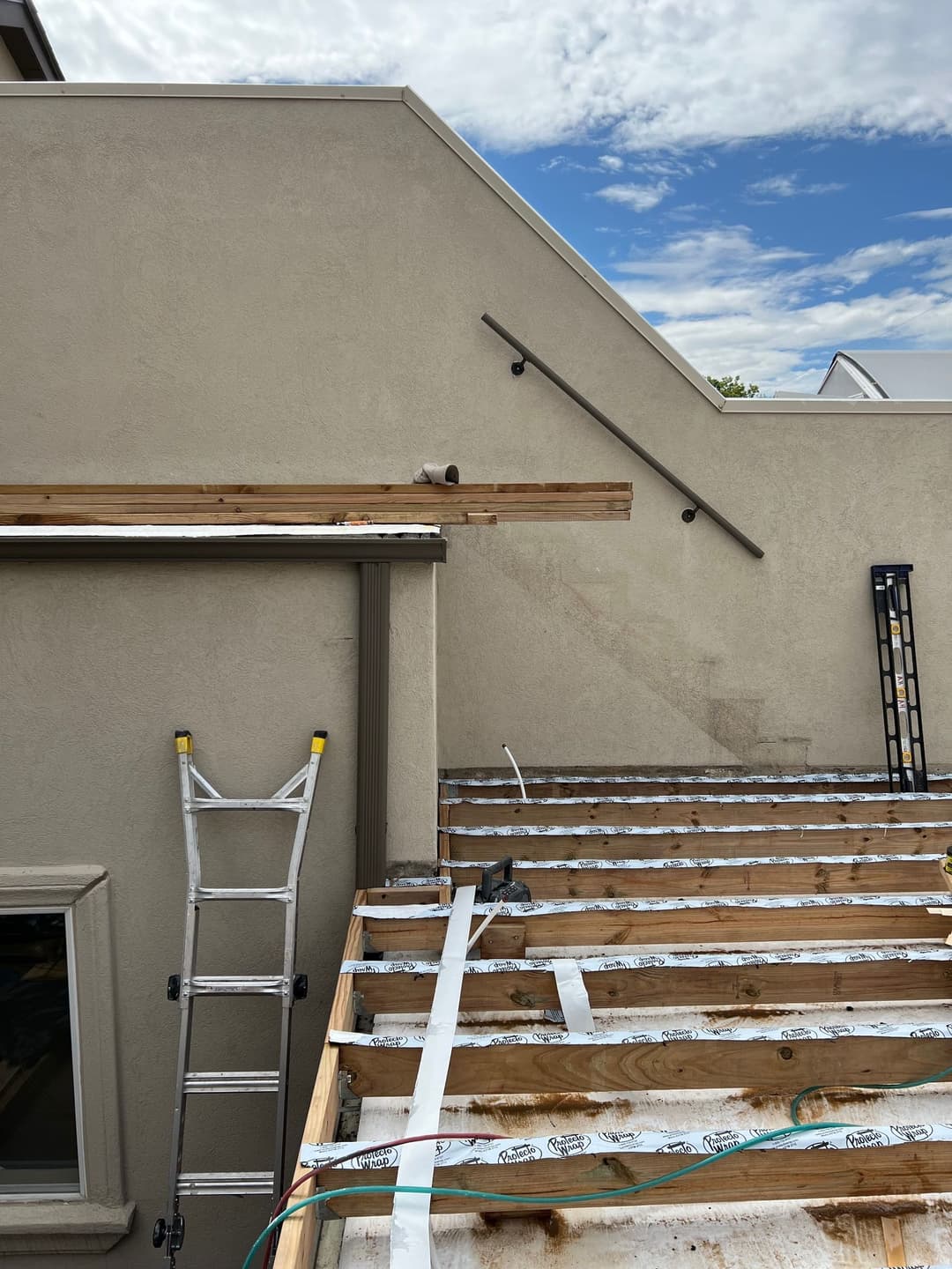 Construction site with wooden decking, ladder, and clear blue sky in background.