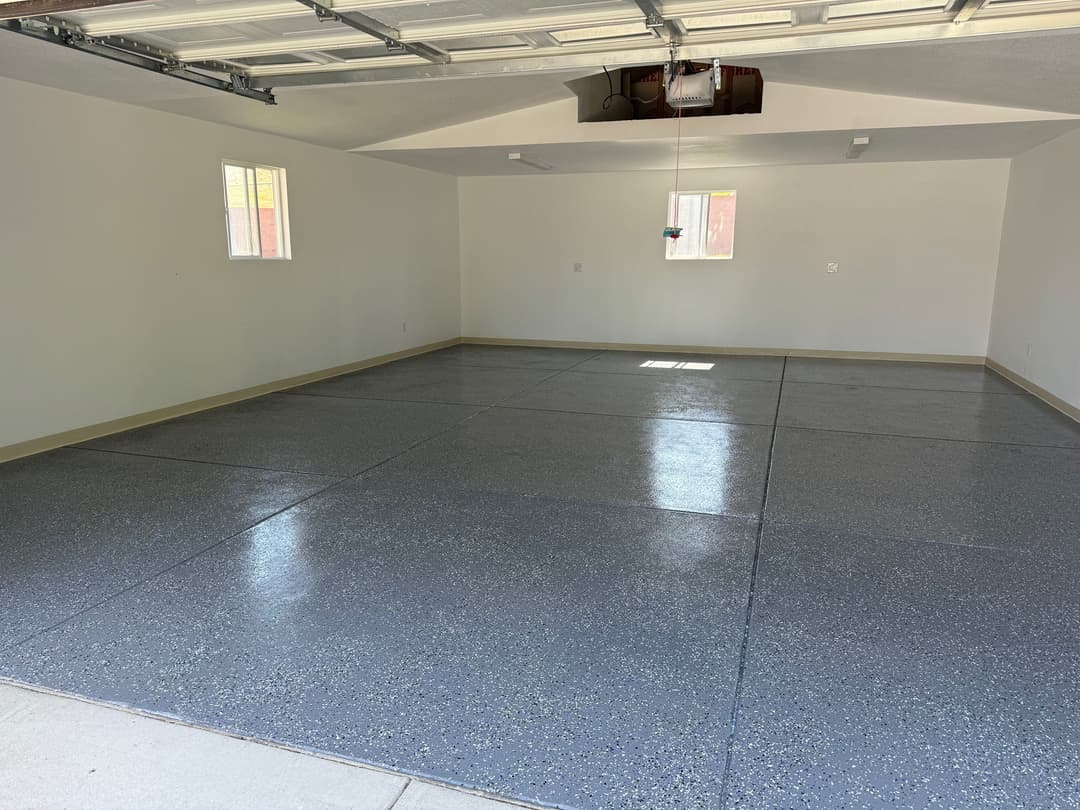 Empty garage with polished concrete floor and sunlight streaming through windows.