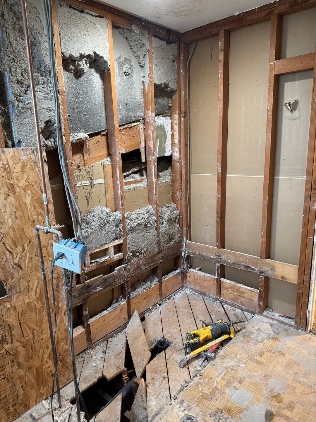 Renovation progress showing exposed studs and damaged drywall in a home interior.