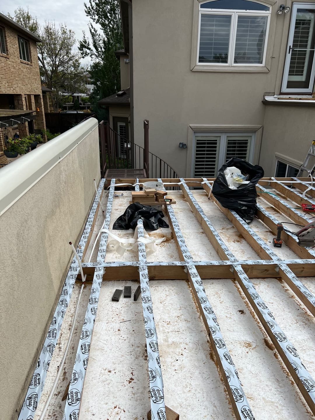 Roof construction with wooden beams and protective covering under a clear sky.