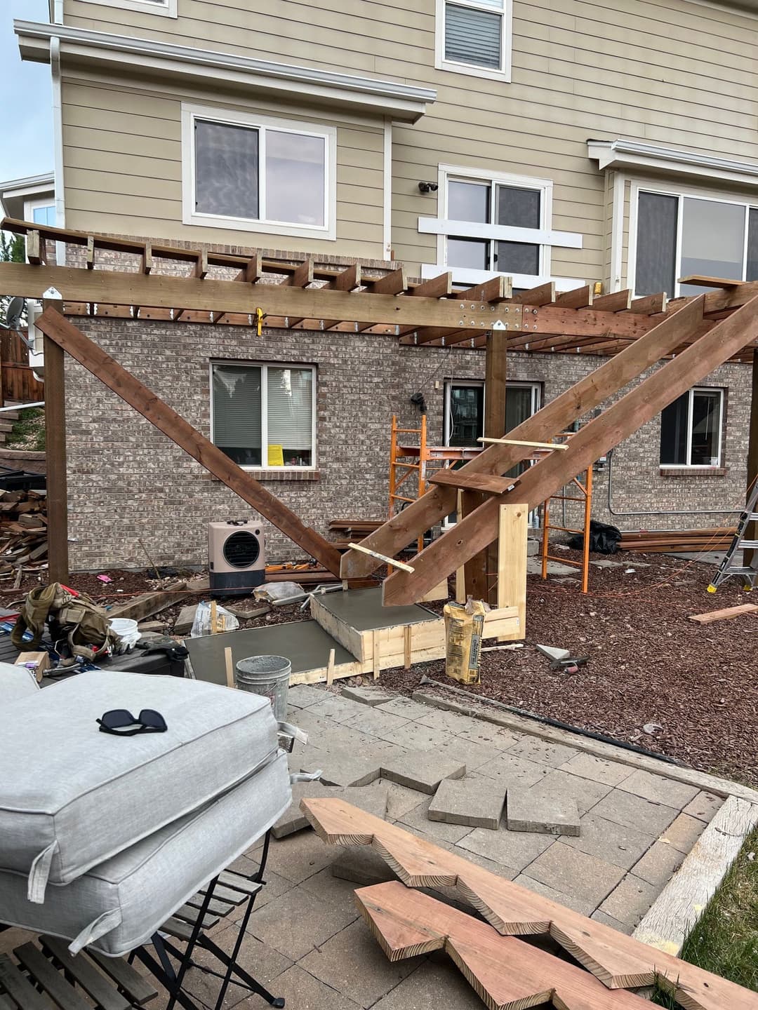 Wooden deck structure under construction beside a house, with tools and materials visible.