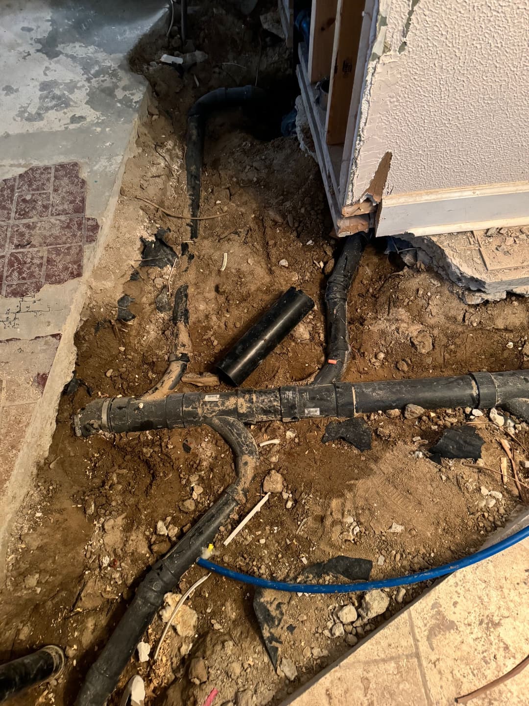 Exposed PVC pipes and trenches in a renovation project showcasing plumbing work.