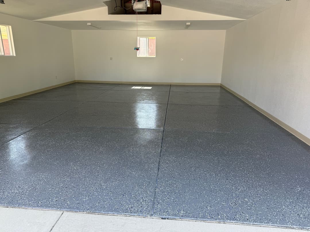 Empty garage interior with polished gray flooring and natural light from windows.