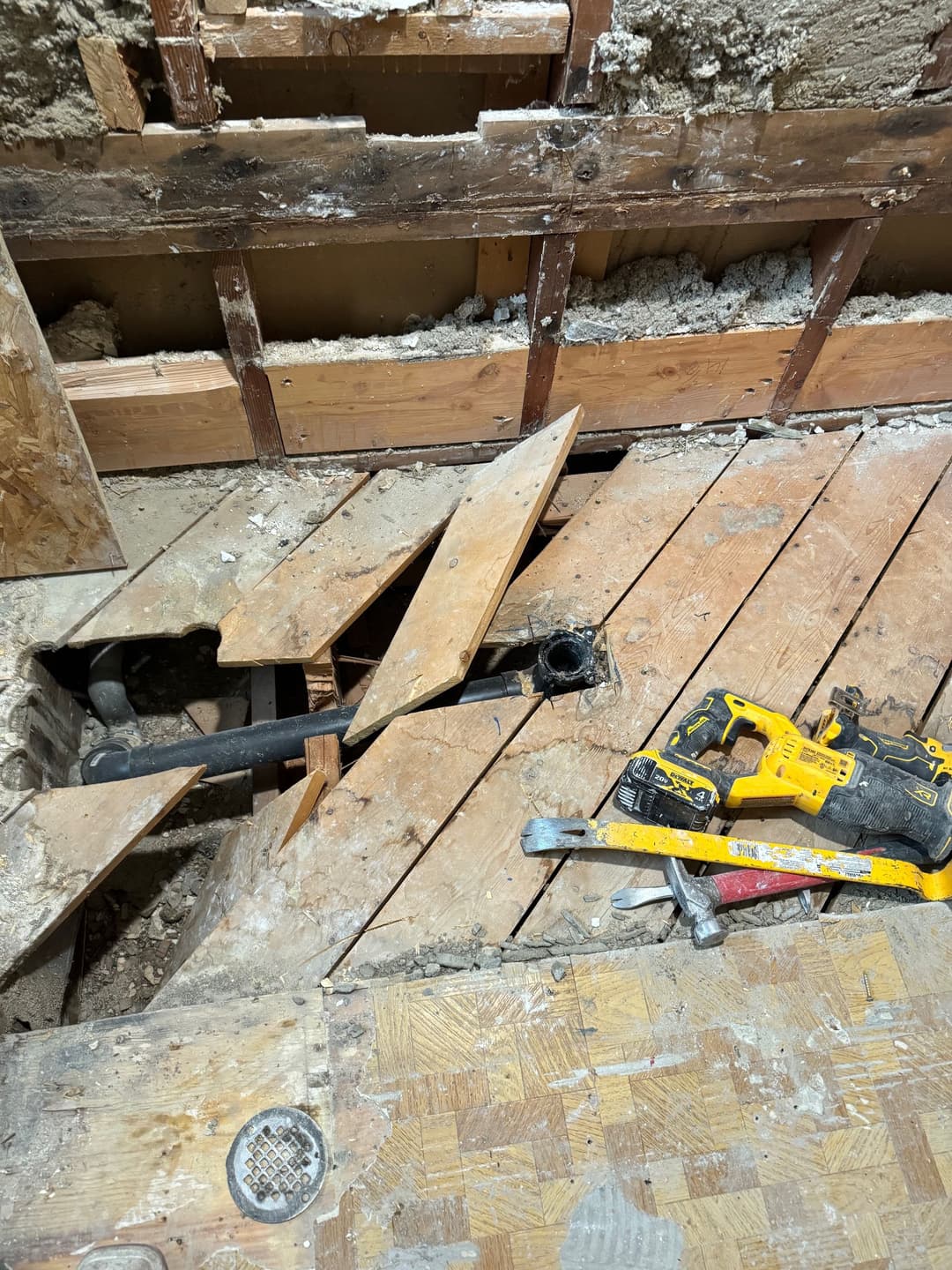 Exposed floorboards and plumbing in a home renovation project with tools nearby.